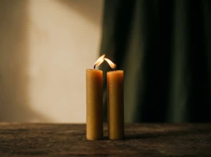Two candles burning close together, their flames beginning to merge, symbolizing emotional and physical intimacy.